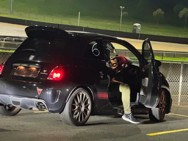 Club members inspecting the custom 16-valve engine bay of a modified Fiat X1/9.